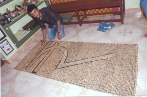 MOSAIC OF RUPEE SYMBOL USING PISTA AND GROUNDNUT SEED COATS